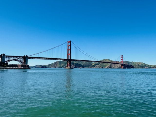 Golden Gate Bridge in San Francisco on a clear day with a sailboat passing beneath, symbolizing the best time to visit the city