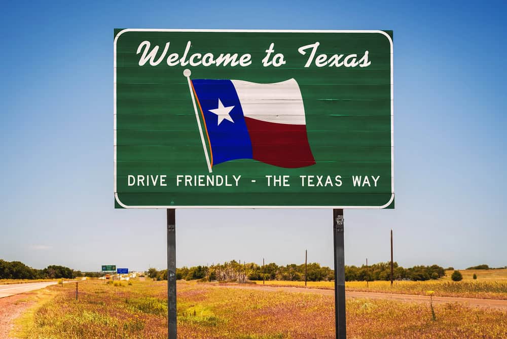 Welcome to Texas green roadside sign with the Texas flag and slogan “Drive Friendly – The Texas Way” near a wide-open highway