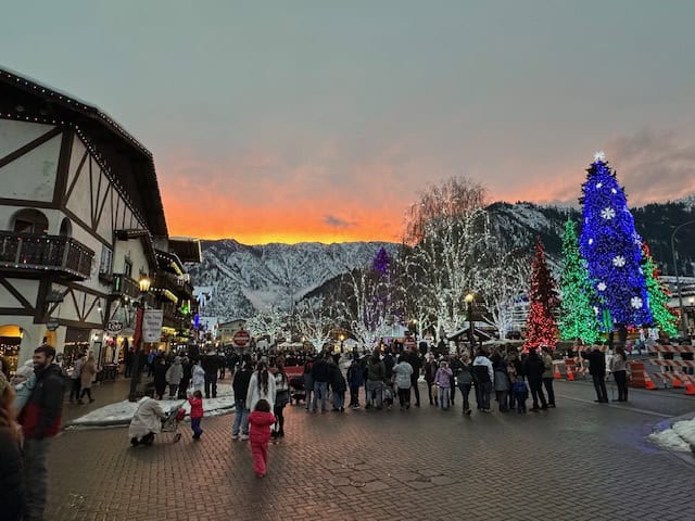 Fiery sunset over Leavenworth WA’s main street with Bavarian-style buildings lit up in Christmas lights