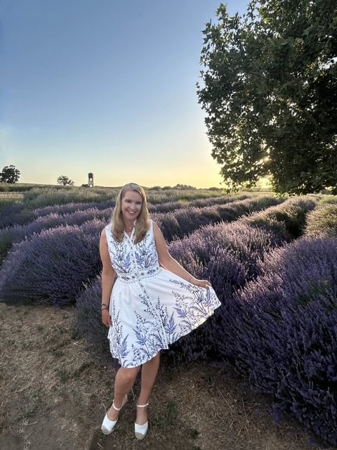 Midlife woman twirling in a lavender field holding her dress enjoying the lavender field.