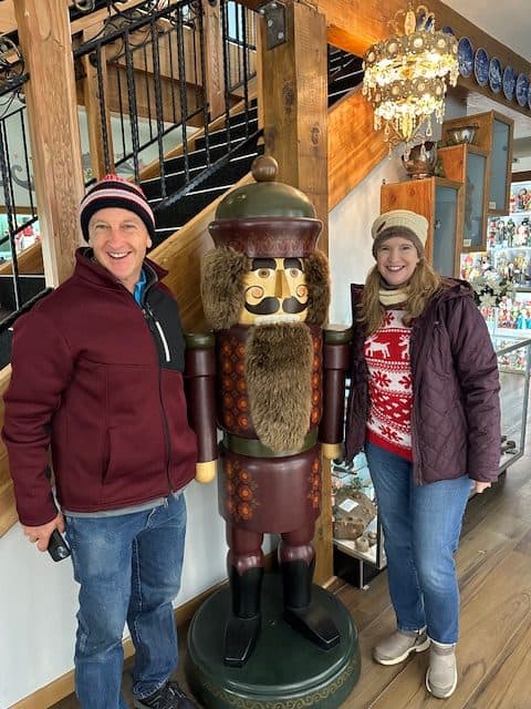 Couple standing beside a giant Nutcracker statue at the Nutcracker Museum in Leavenworth, Washington