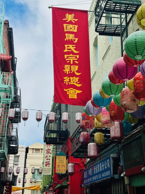 Colorful lanterns and Chinese banners hanging above a narrow street in San Francisco’s historic Chinatown
