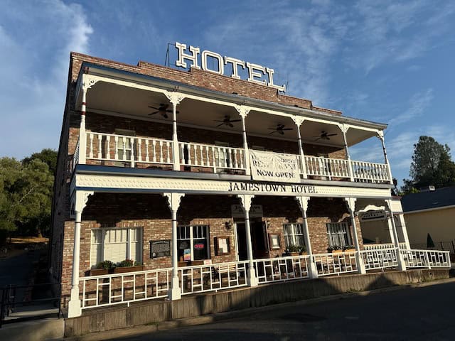 Historic Jamestown Hotel in California’s Gold Country with a two-story brick façade, white balconies, and classic Western charm under a bright blue sky