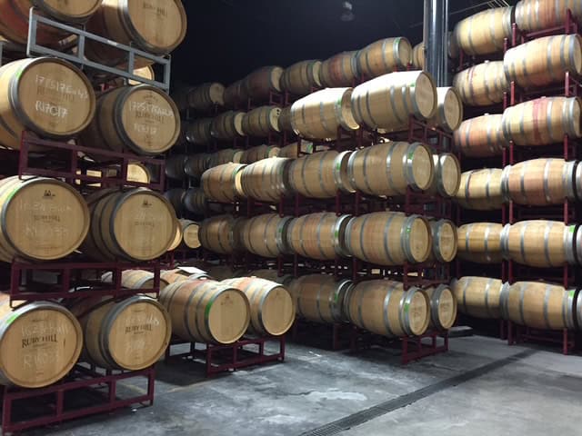 Wooden wine barrels stacked in rows inside Ruby Hill Winery’s barrel room in Livermore, California — part of a Livermore Valley wine tasting tour experience.