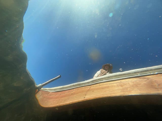 Underwater view from Gull Lake showing a wooden dock and a traveler above the surface, captured accidentally after a phone fell into the lake during a fall trip to June Lake, California