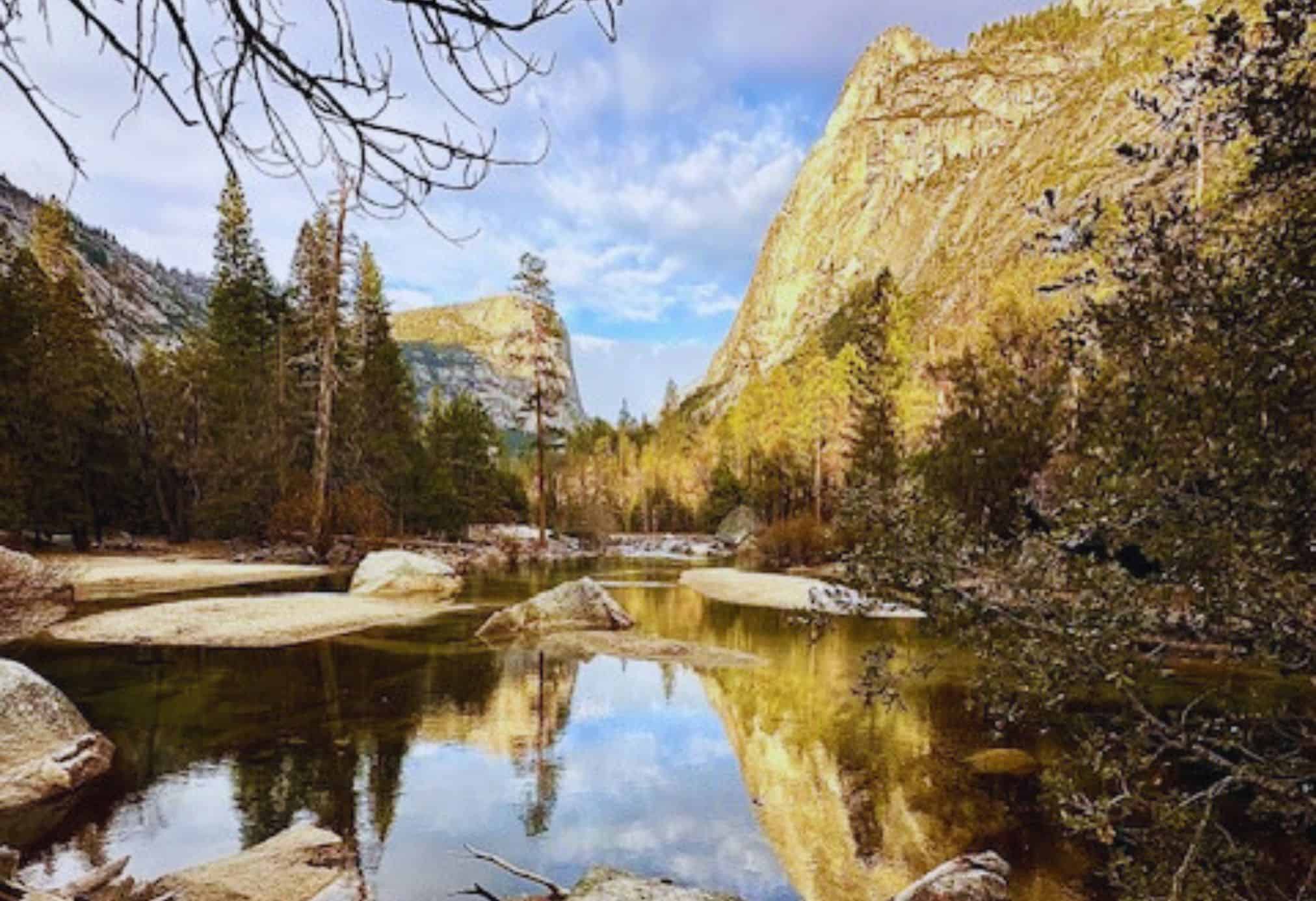 Mirror Lake in Yosemite National Park reflecting the surrounding granite cliffs, pine trees, and golden afternoon light on a calm spring day