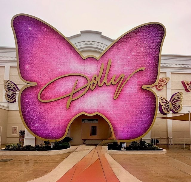 Pink butterfly-shaped Dolly Parton display outside a Pigeon Forge attraction, featuring the word Dolly and decorative butterflies