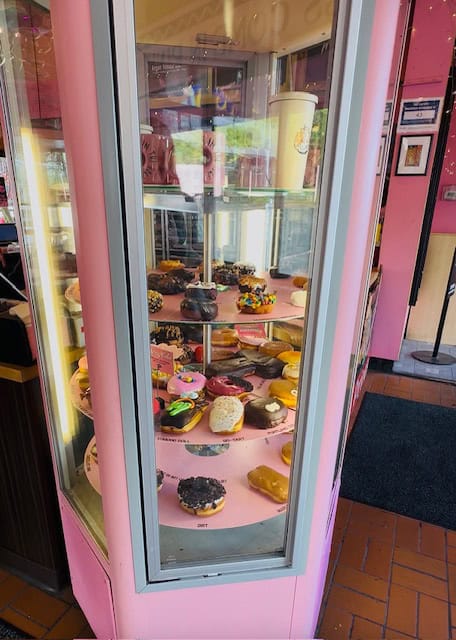 Colorful assortment of Voodoo Doughnuts inside a pink display case in Portland, Oregon featuring iconic toppings and quirky designs