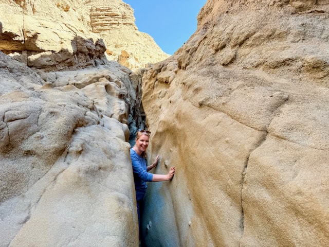 Woman walking through narrow slot canyon walls in Anza Borrego Desert State Park