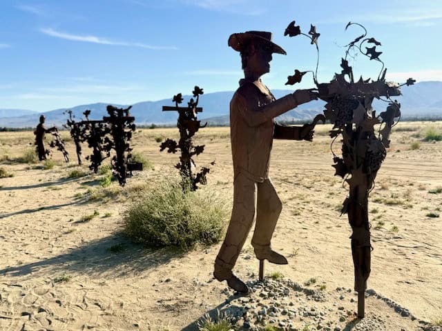Metal vineyard worker sculptures in Galleta Meadows in Anza Borrego Desert with mountains in the background