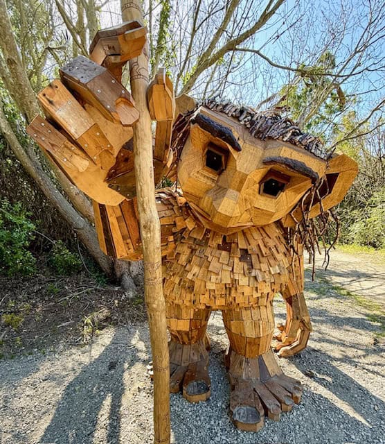 Wooden troll sculpture holding a walking stick at South Coast Botanic Gardens, large recycled wood art with detailed face in outdoor setting