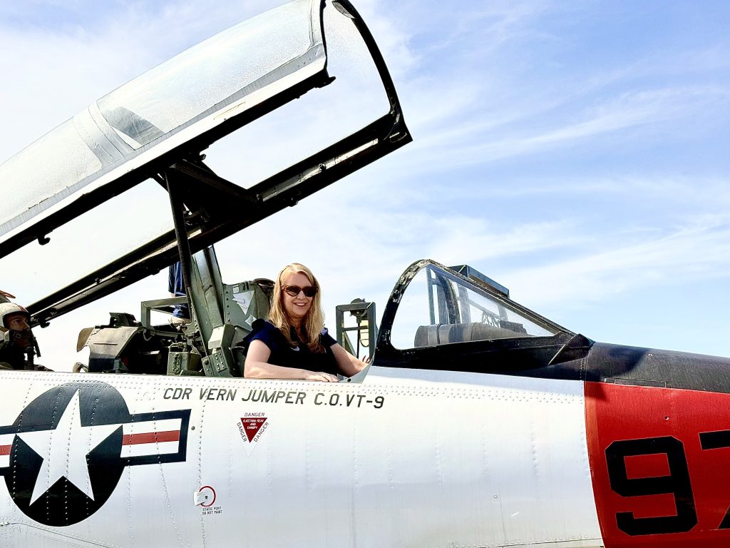 Visitor sitting in the cockpit of a historic fighter aircraft at the USS Midway Museum in San Diego, a must-visit stop on a 3 Day San Diego Itinerary