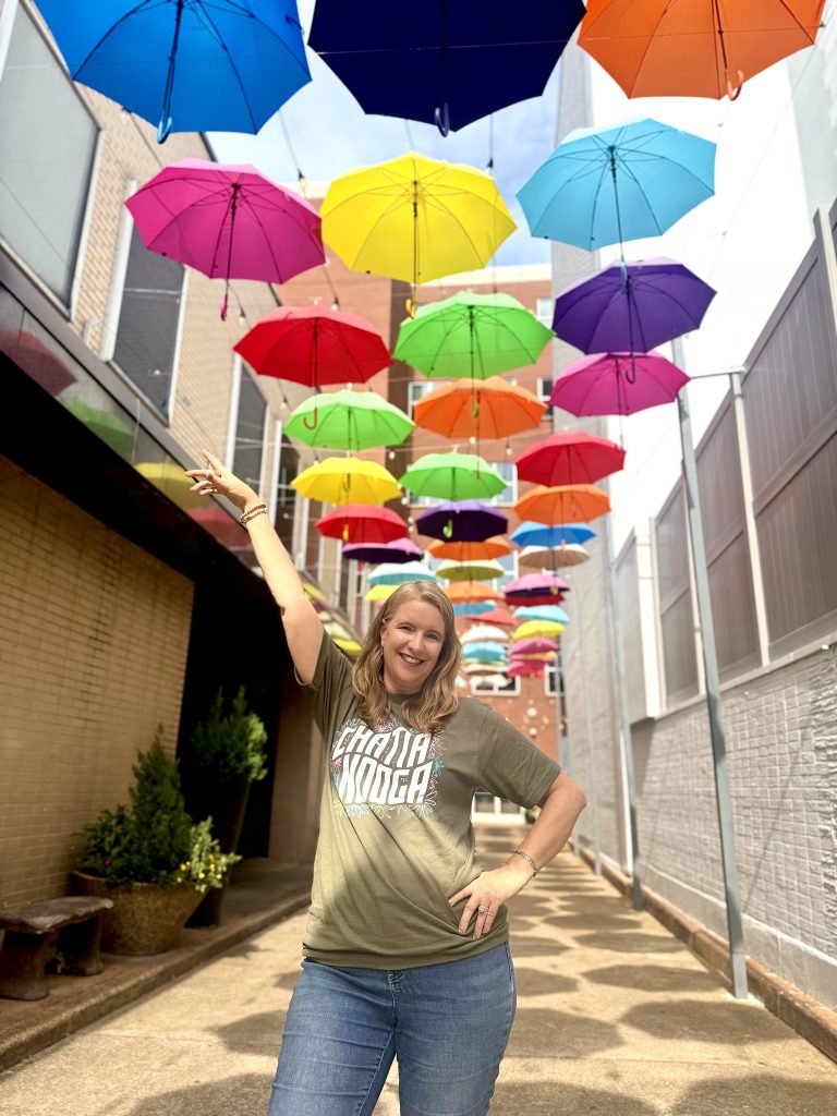Woman posing beneath colorful umbrella alley installation in downtown Chattanooga, Tennessee