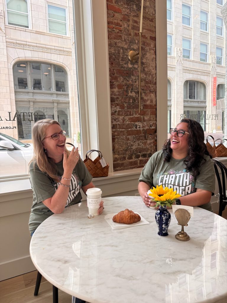 Two women enjoying coffee and a fresh croissant inside Petal Pour café in downtown Chattanooga during a Chattanooga 2 Day Itinerary