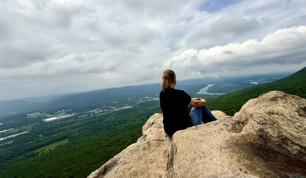 Traveler sitting on Sunset Rock overlooking the Tennessee River and surrounding mountains in Chattanooga, Tennessee, during a Chattanooga 2 day itinerary
