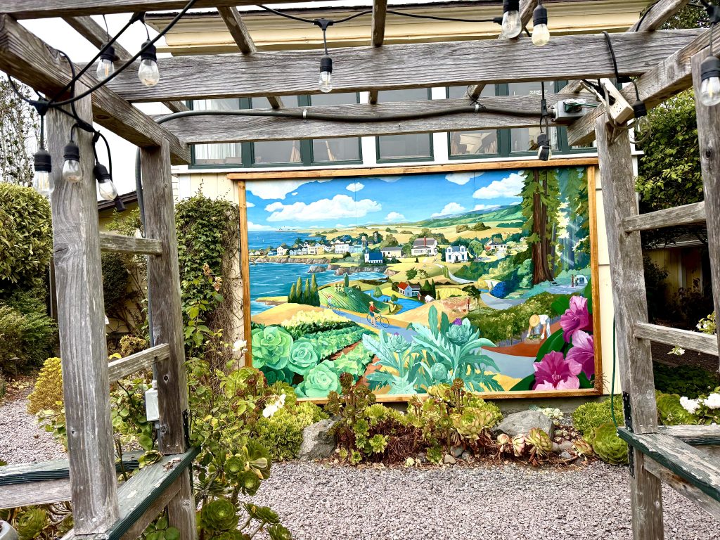 Colorful coastal mural beneath a wooden garden arbor at The Brickery during a girls weekend in Mendocino, California