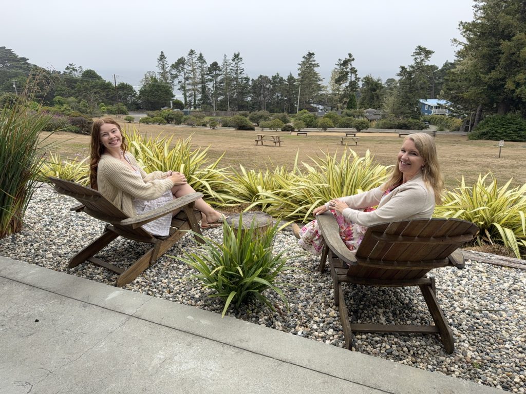 Two women relaxing in Adirondack chairs outside Seafoam Lodge during a girls weekend in Mendocino, California